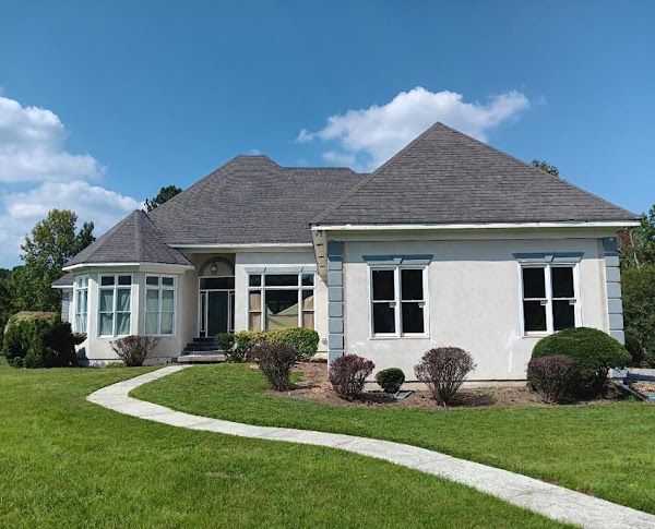 A white house with a gray roof and a walkway leading to it