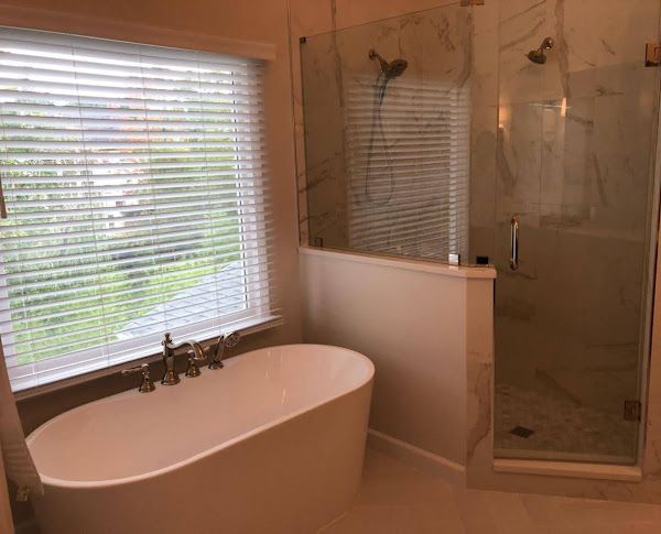 A bathroom with a tub, shower, and window
