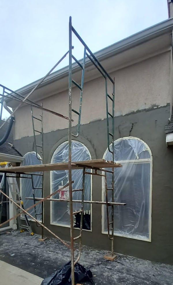 A scaffolding is sitting in front of a building that is being painted