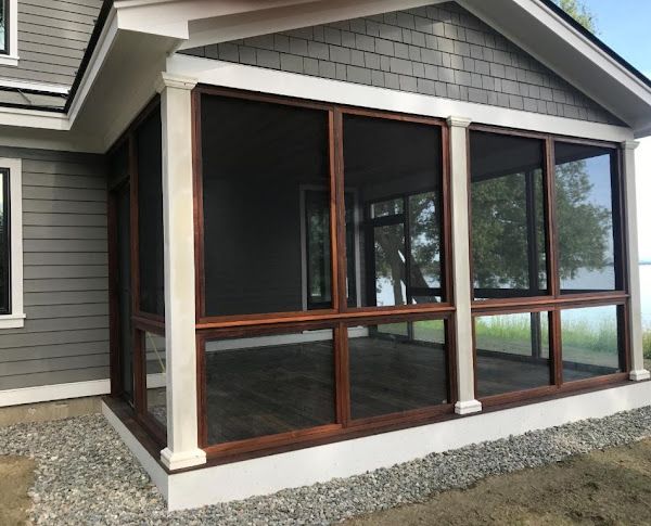 A screened in porch with a lot of windows on the side of a house