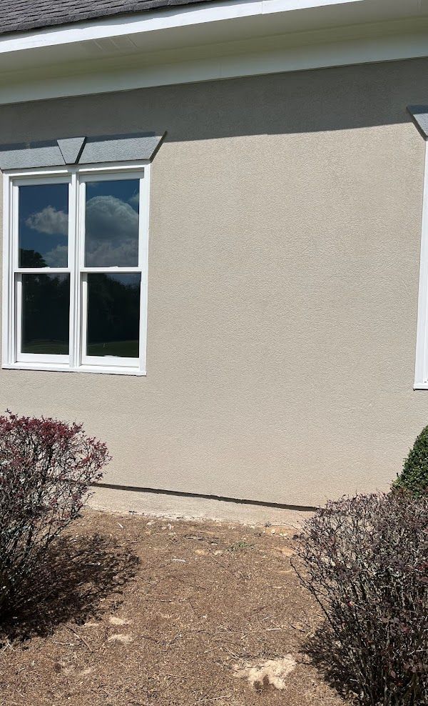 A house with a lot of windows and bushes in front of it