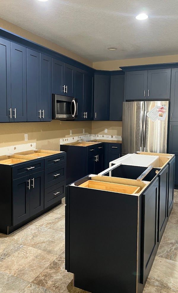 A kitchen with blue cabinets and stainless steel appliances is being remodeled
