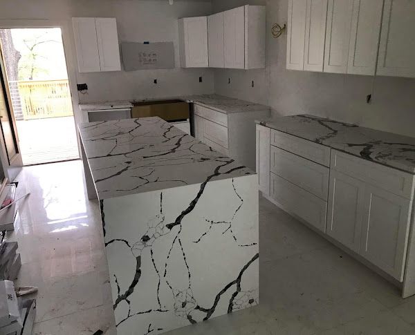 A kitchen with white cabinets and black and white granite counter tops.
