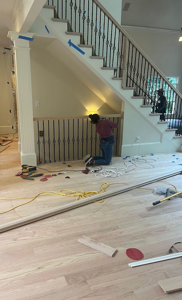 A man is kneeling on the floor in front of a staircase.