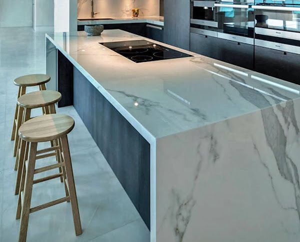 A kitchen with marble counter tops and wooden stools