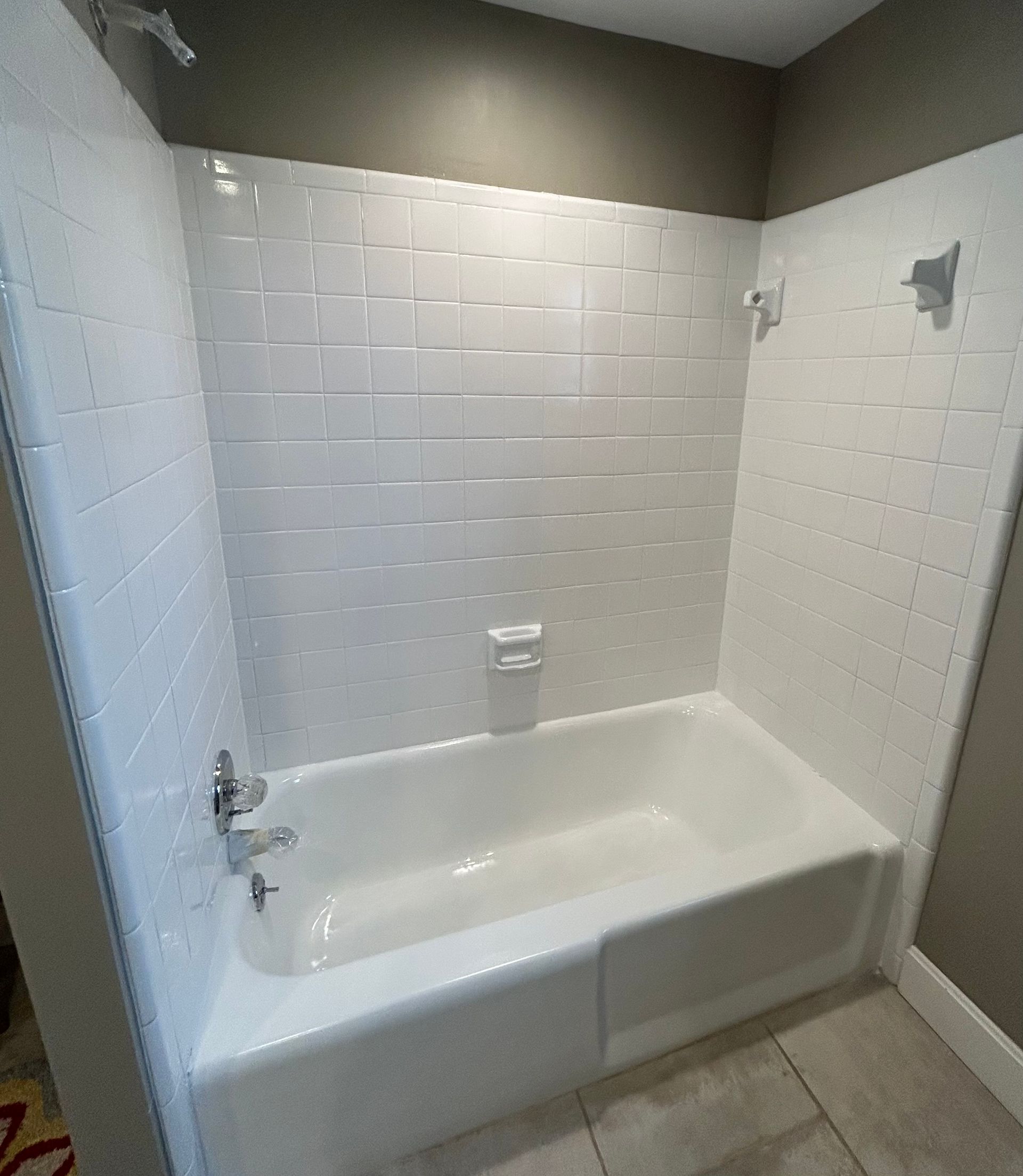 White-tiled shower stall with a bathtub. White and gray with a chrome faucet.