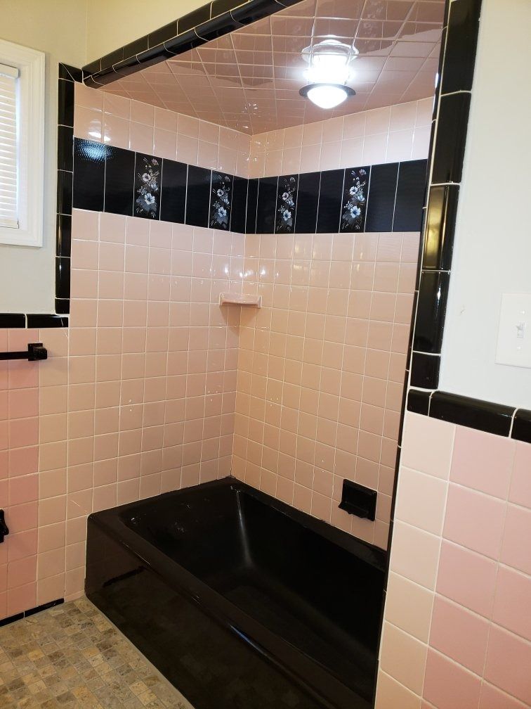 Pink tiled bathroom with black trim and tub.