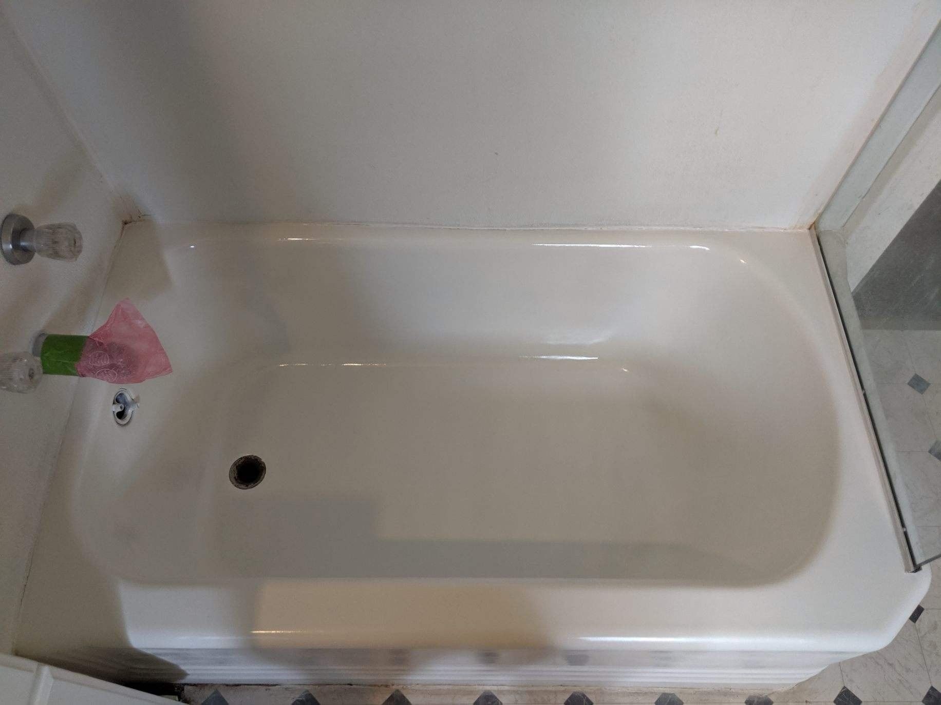 White bathtub in a bathroom with a shower door on the right side.