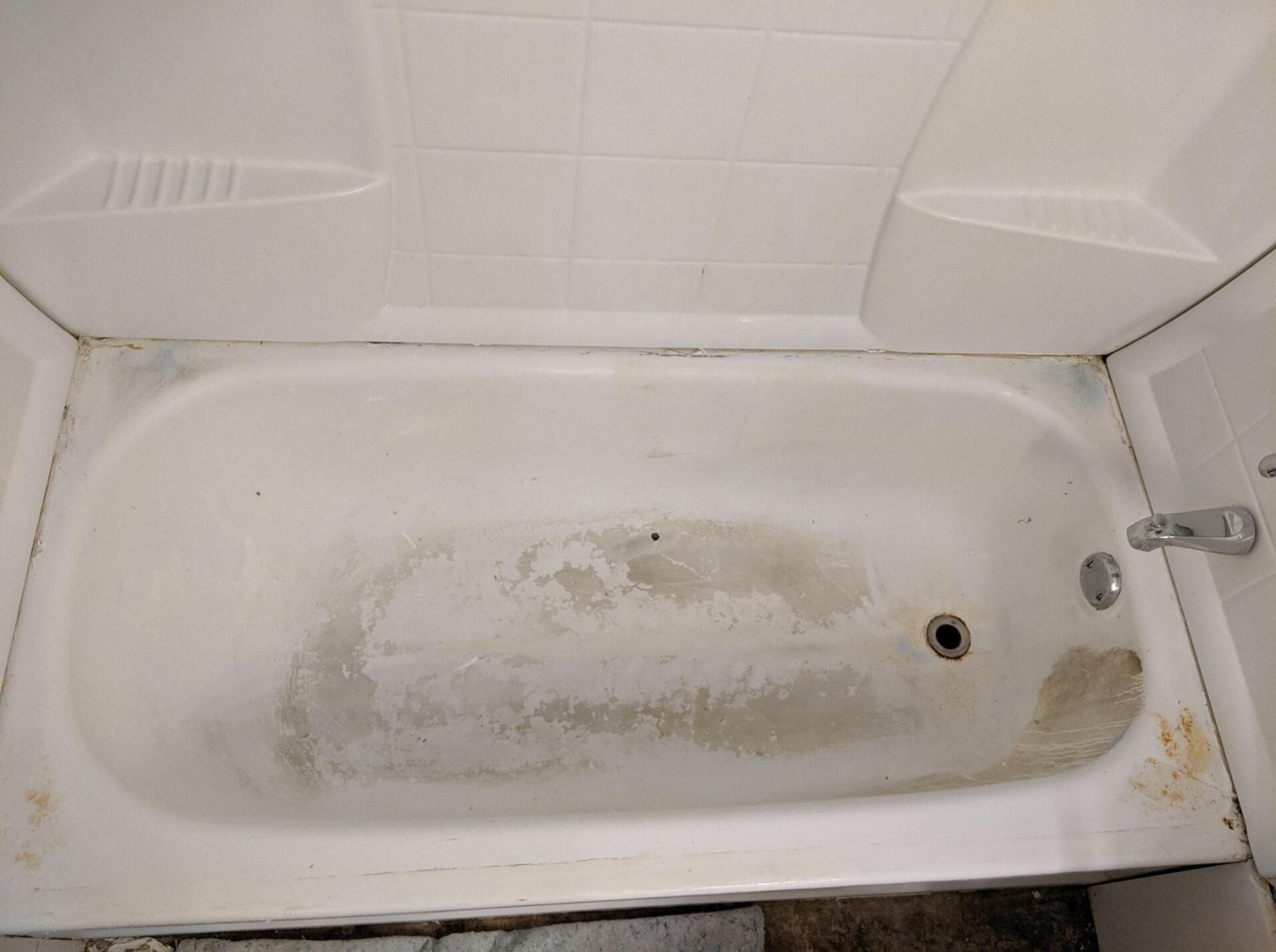 Dirty white bathtub with stains and grime.