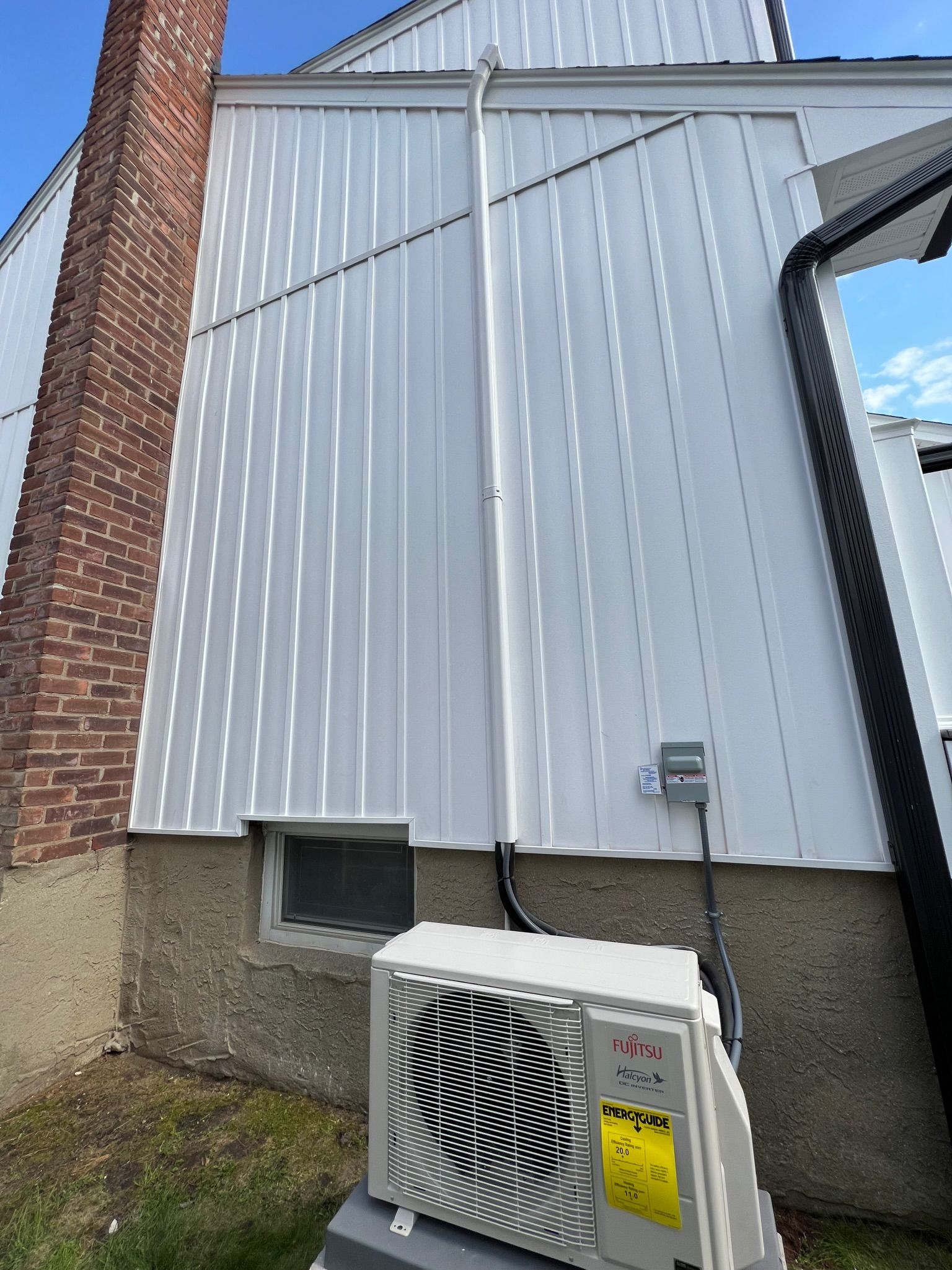a white air conditioner is sitting on the side of a house
