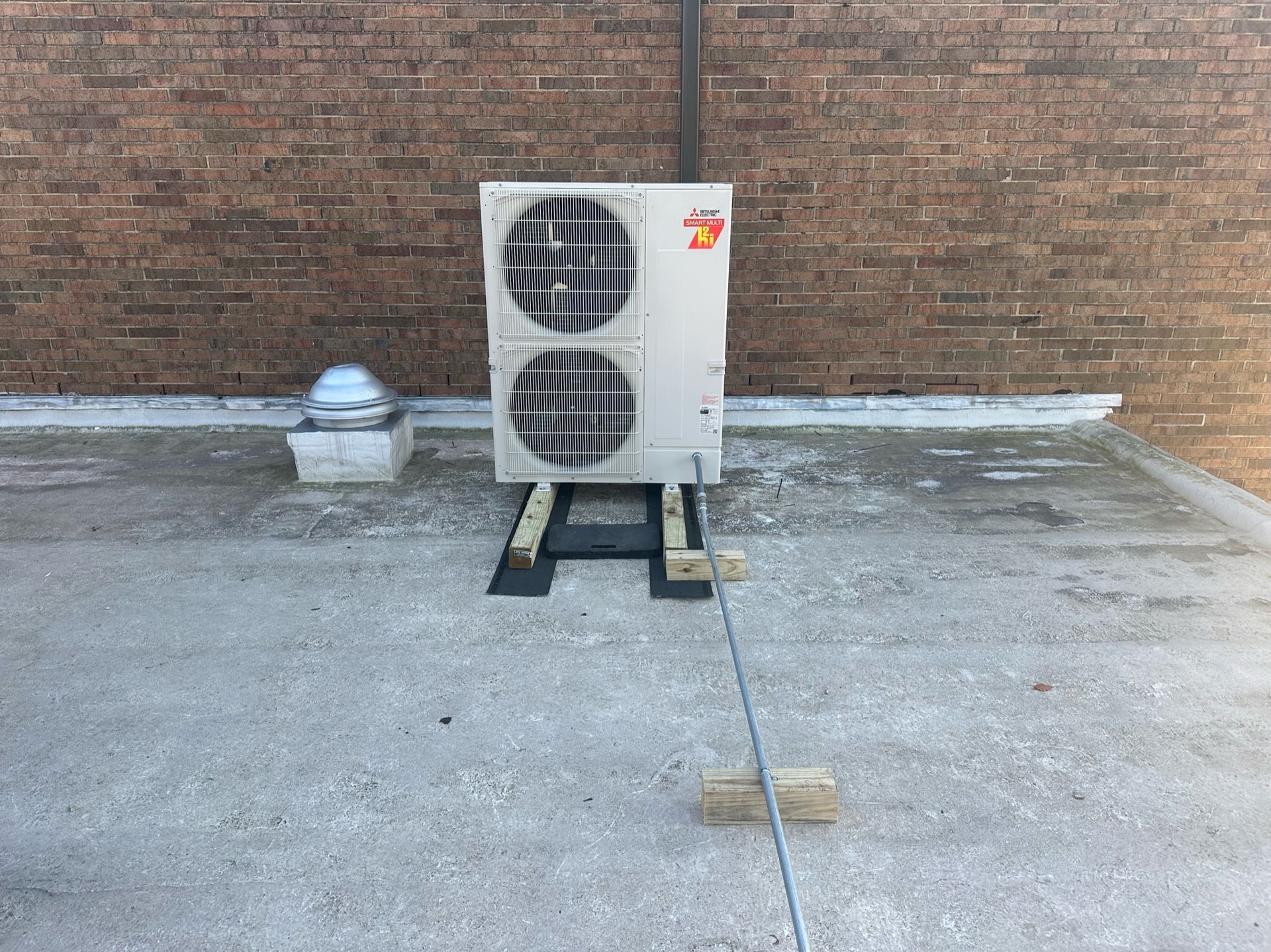 a large air conditioner is sitting on the ground in front of a brick wall