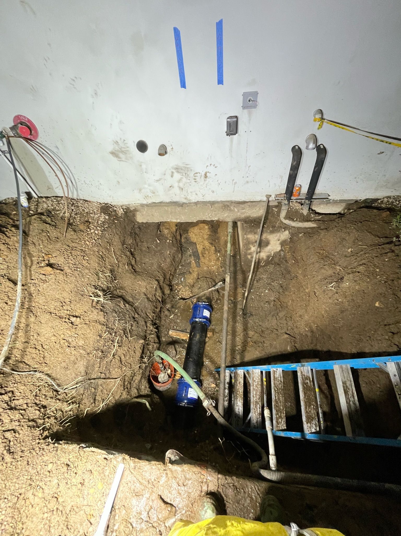 a ladder is sitting in the dirt next to a pipe