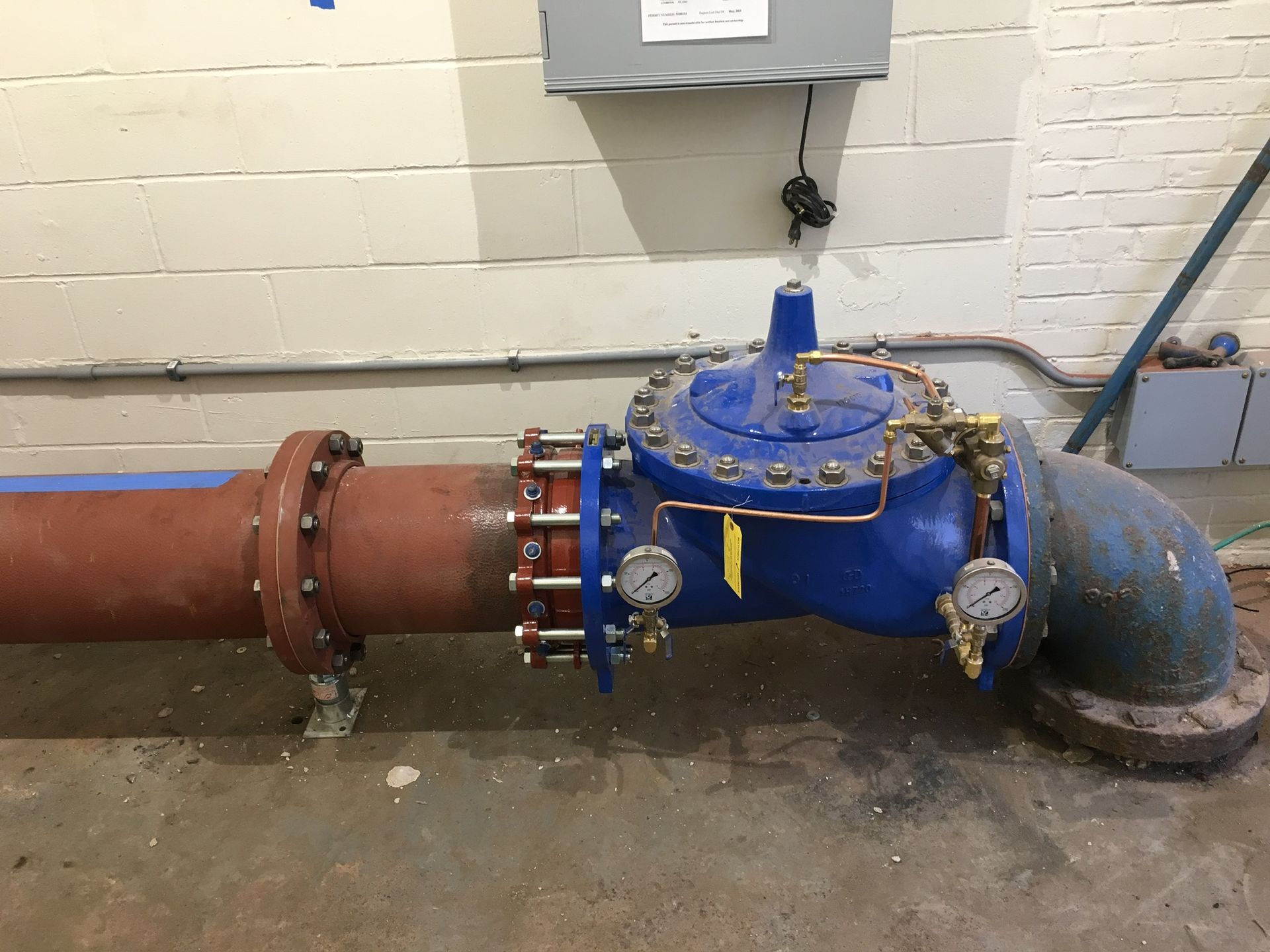 a blue valve is sitting next to a red pipe in a room
