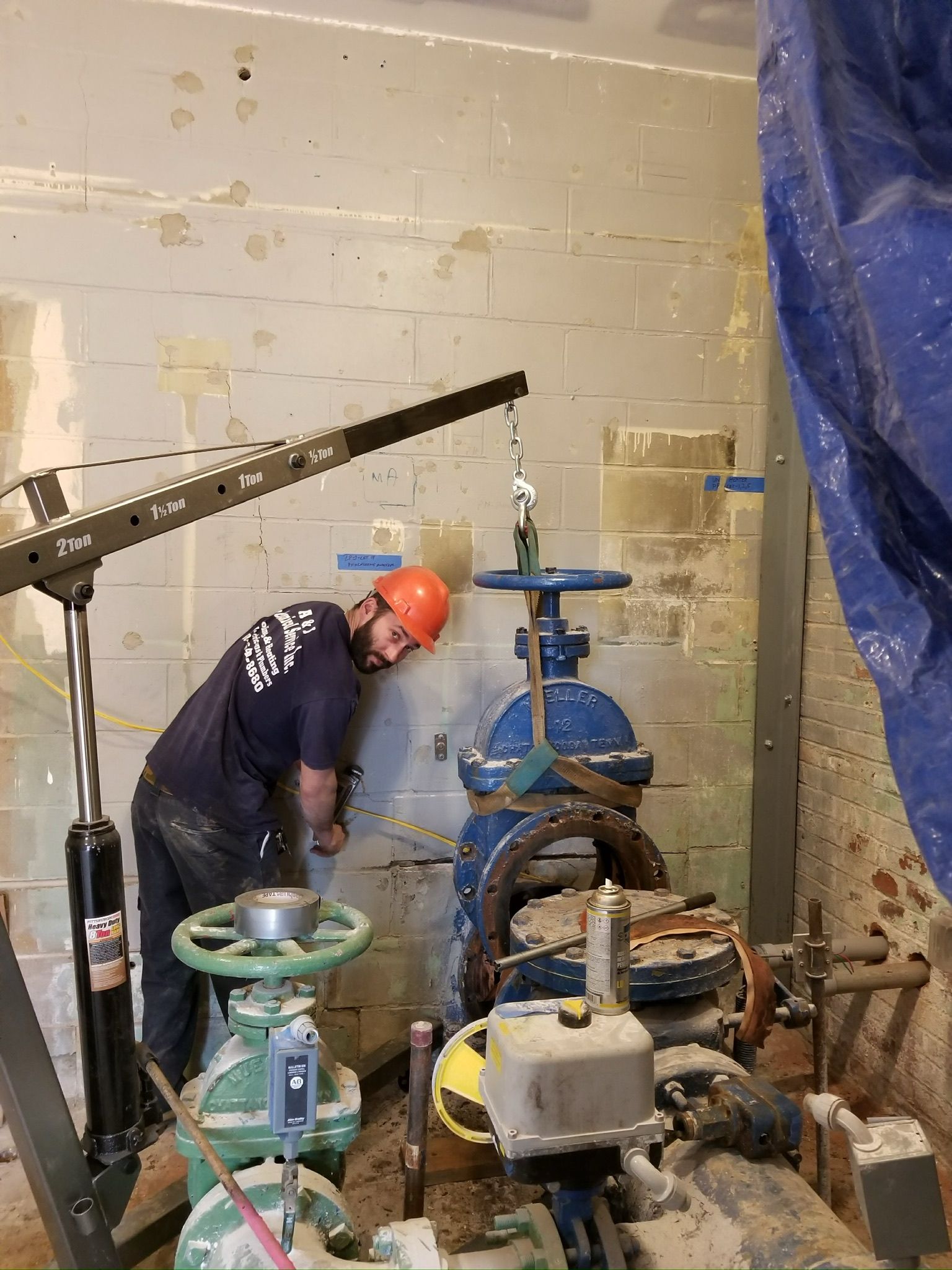 a man wearing a hard hat is working on a pipe in a room