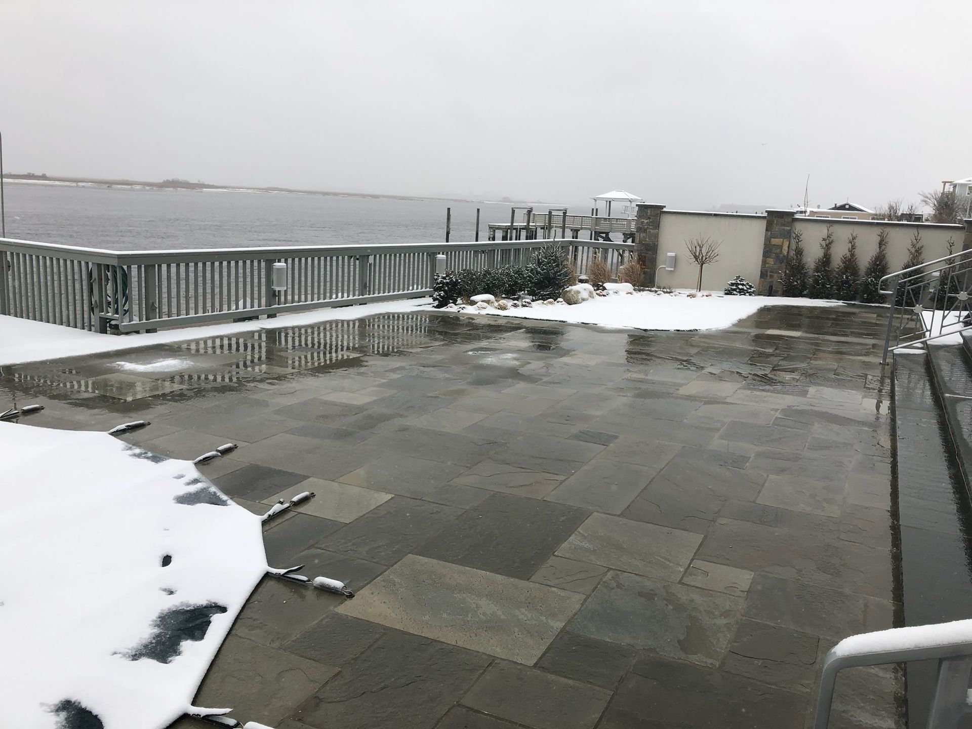 a swimming pool covered in snow with a view of the ocean