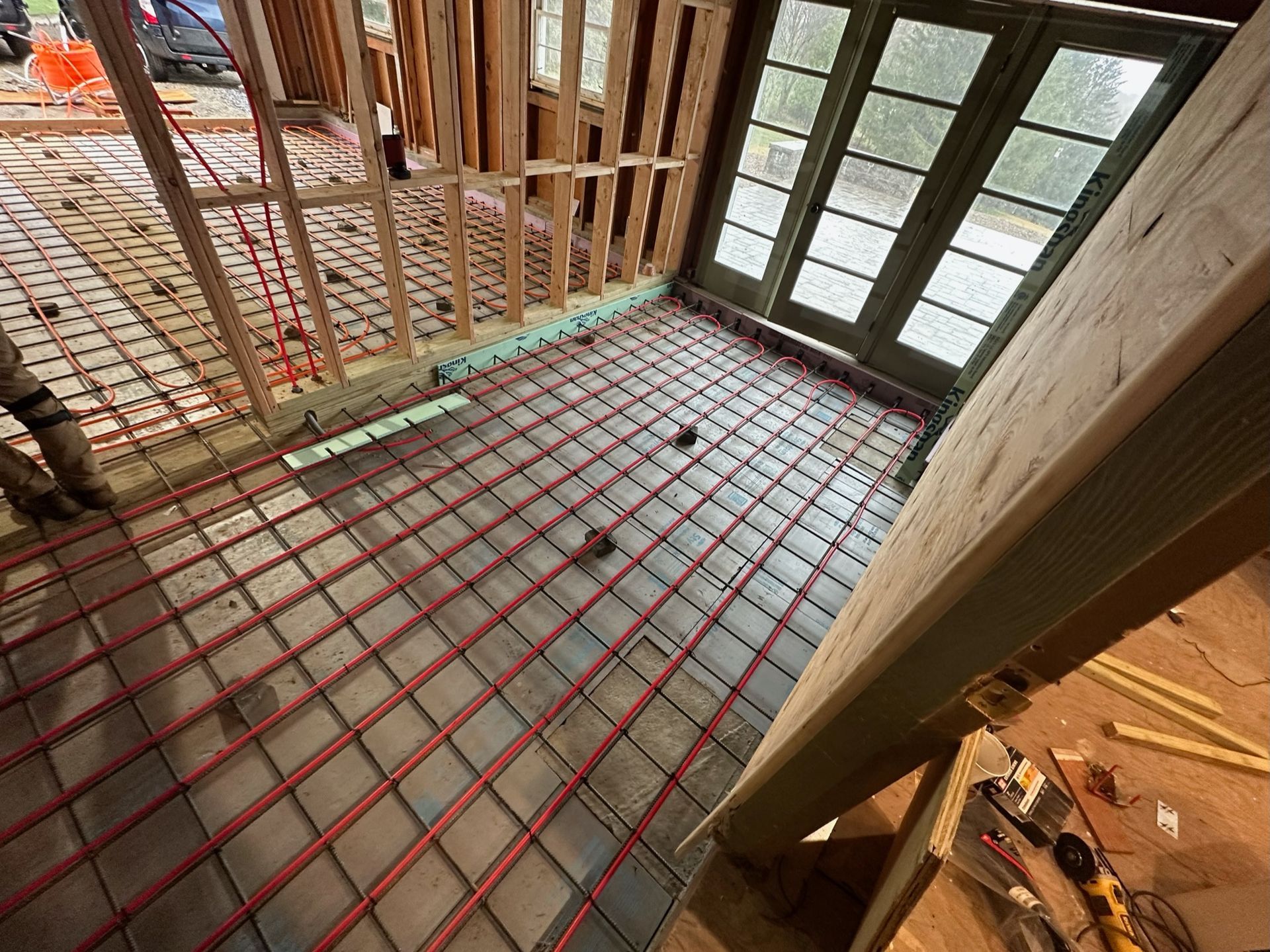 a room under construction with a concrete floor and red pipes