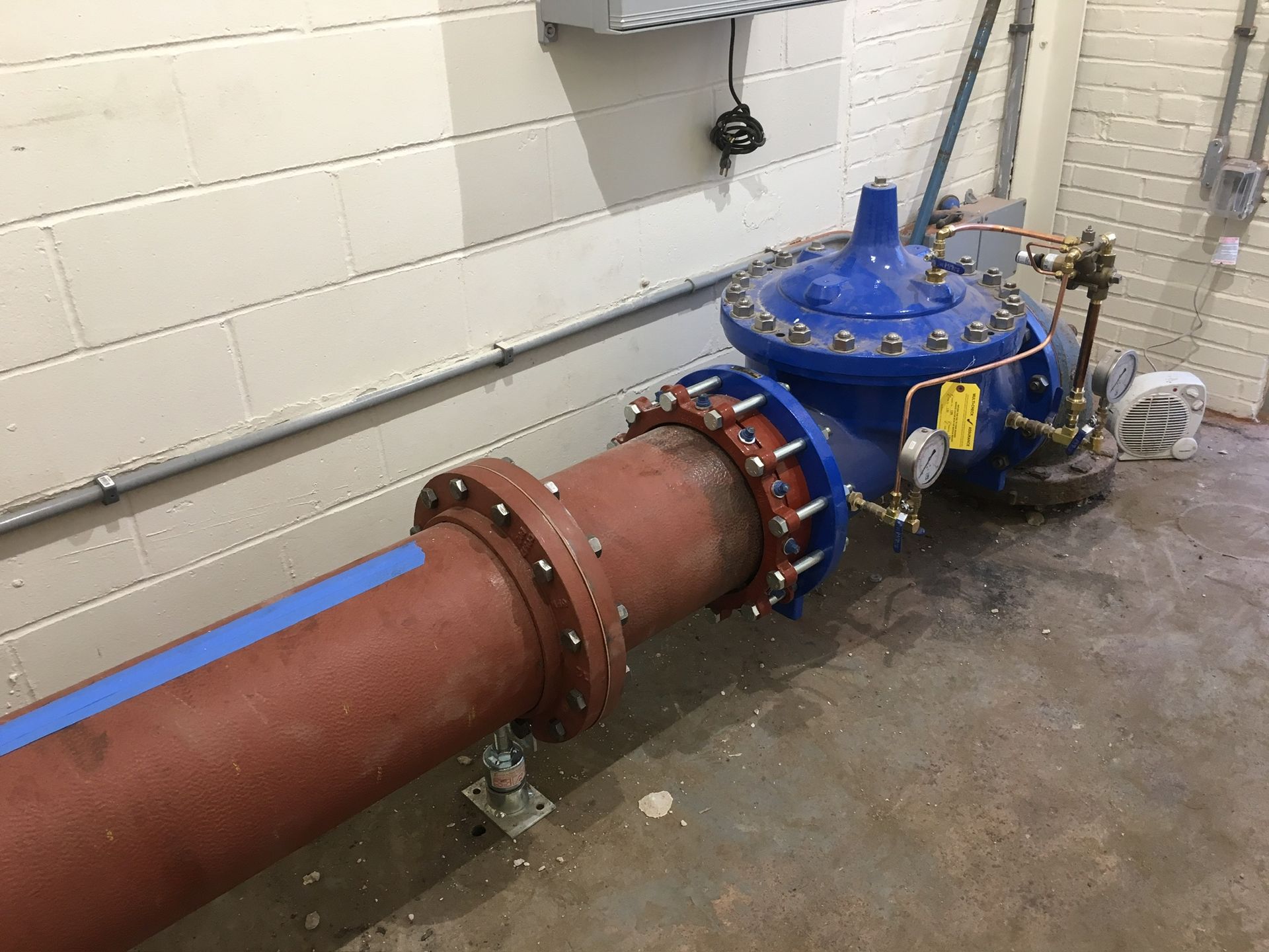 a blue valve is sitting next to a red pipe in a room