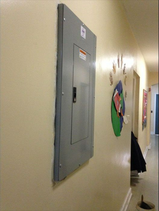 a gray electrical box is hanging on a wall in a hallway