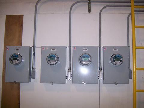 a row of electrical boxes hanging on a wall next to a yellow ladder