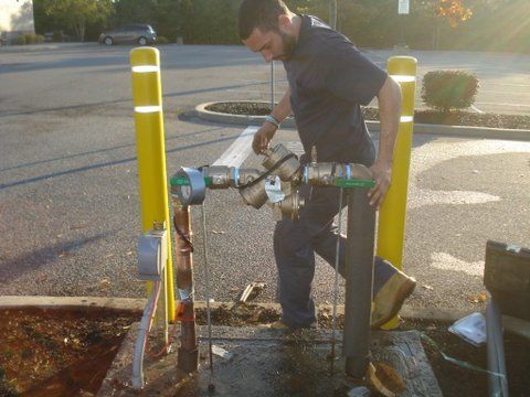 a man is working on a pipe in a parking lot