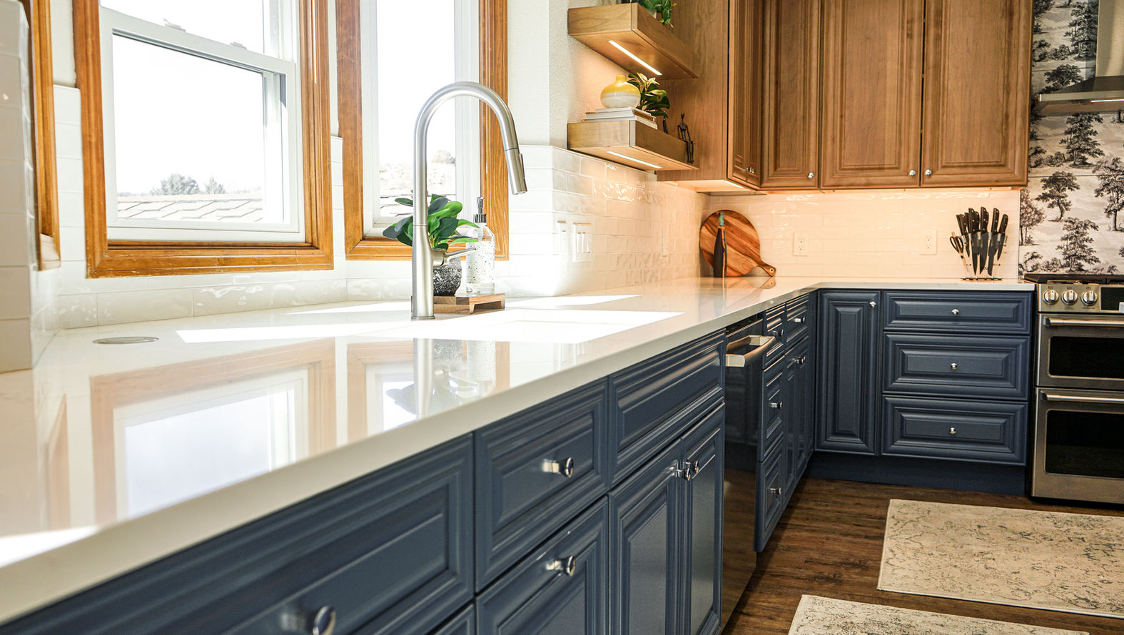 A kitchen with blue cabinets , white counter tops , and a sink.