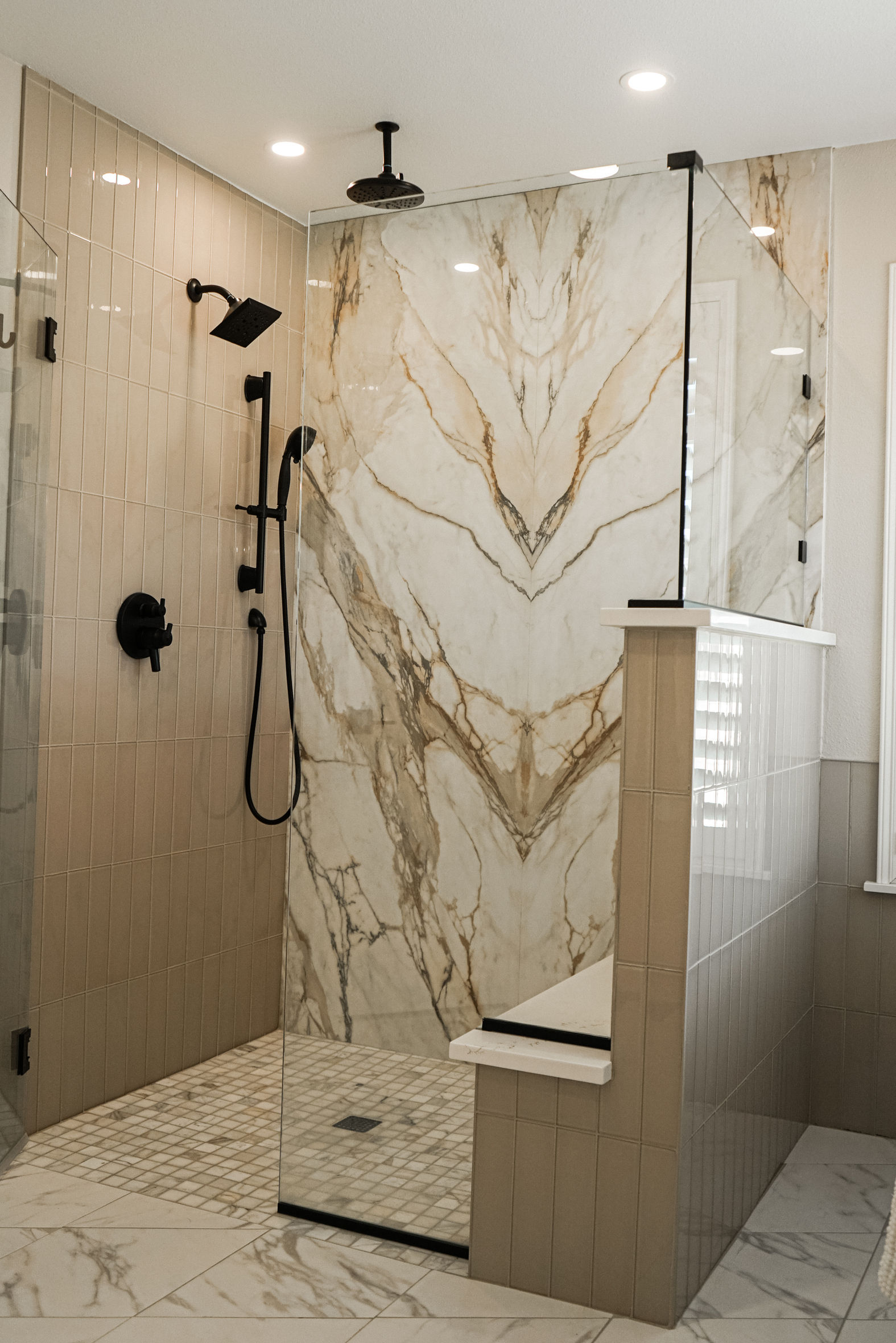 A bathroom with a walk in shower and a marble wall.