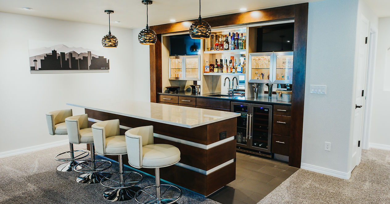 A basement with a bar and stools in it.
