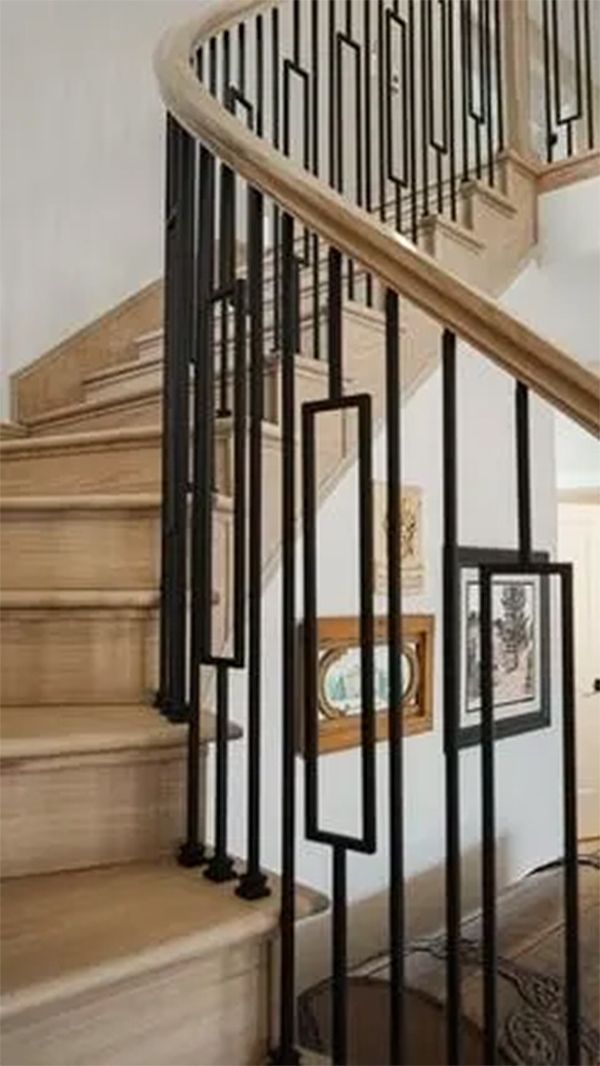Wooden spiral staircase with black metal railing featuring rectangular cutouts and a light-colored wooden handrail.