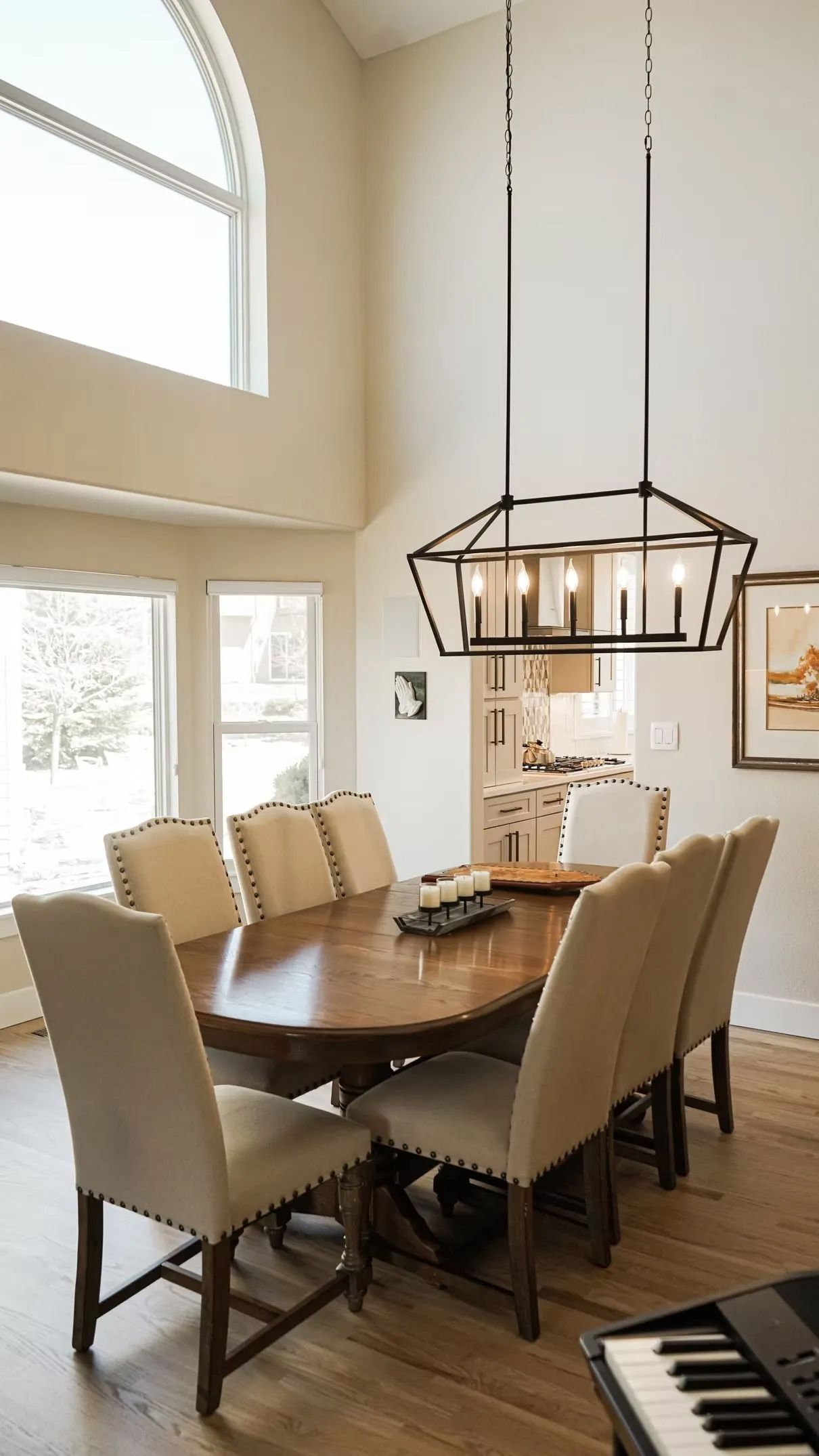 A formal dining room with an oval wooden table and upholstered chairs. A large geometric chandelier hangs overhead.