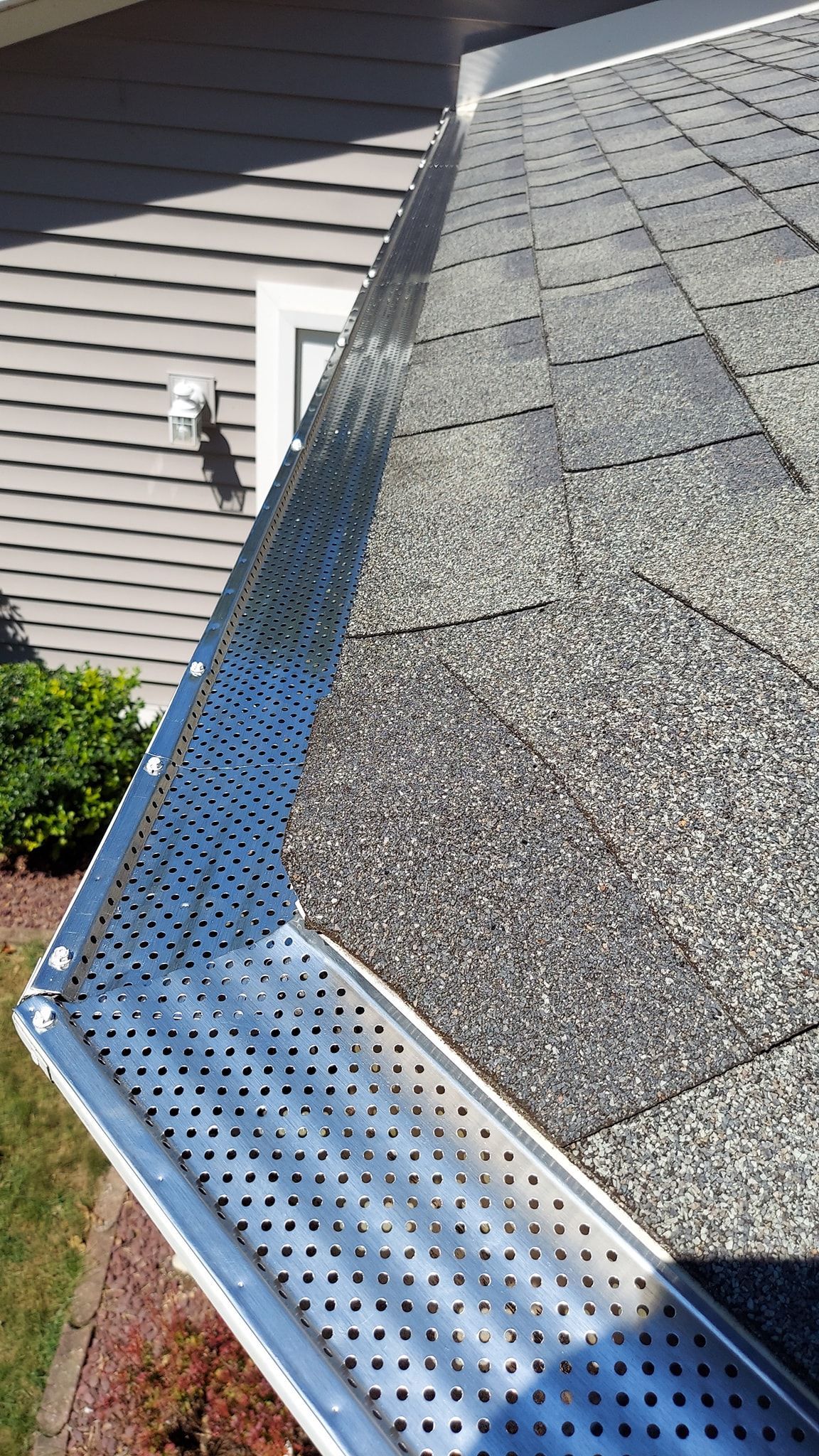 Gutter with metal mesh to prevent debris buildup, on a roof.