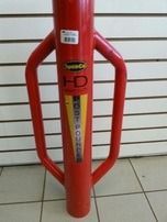 Red metal bollard with yellow safety label in front of a white wall and tiled floor.