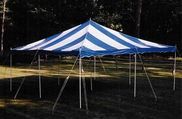 Blue-and-white striped circus tent at night, lit by spotlights and supported by poles