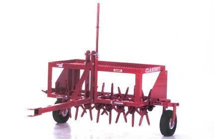 Red agricultural seed drill with tines and wheels on a white background