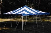 Blue-and-white striped circus tent on a grassy field with support poles