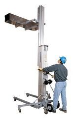 Worker operating a tall wheeled lifting hoist in a white studio setting