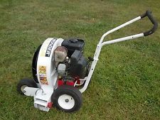 White and black wheeled leaf blower on grass with long handle and large fan housing