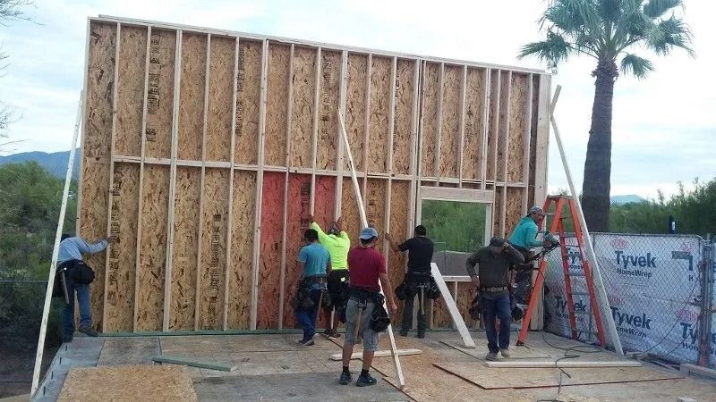 Construction workers framing a wall with window opening outdoors.