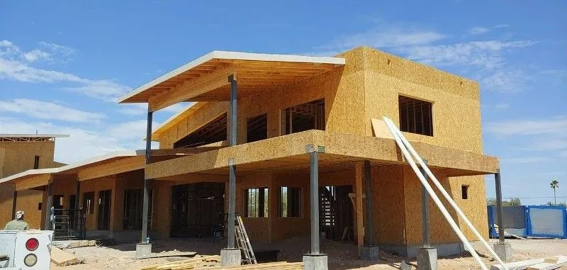 Building under construction with exposed wooden framework, blue sky background.