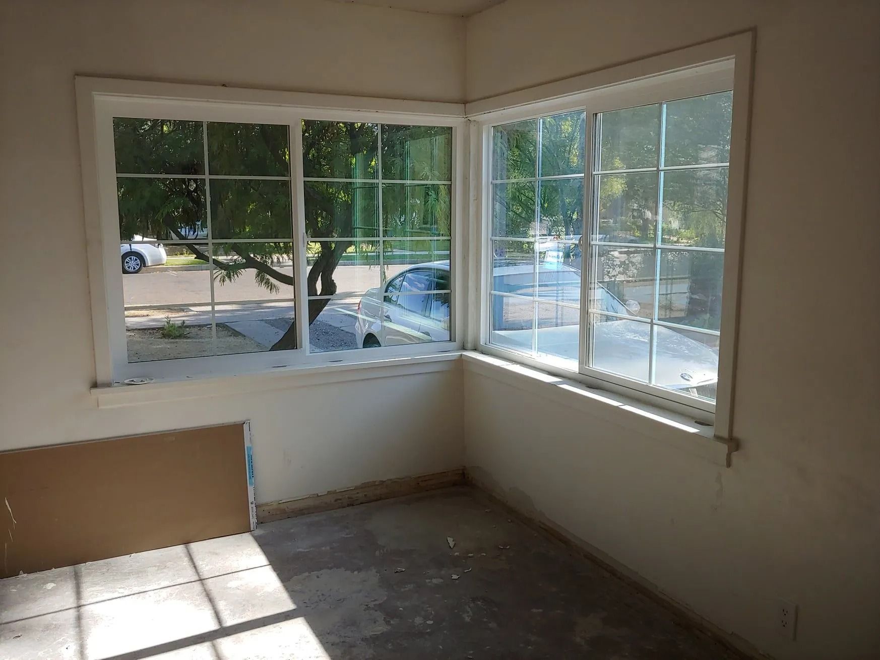 Corner room with two windows, a street view, and sunlight.