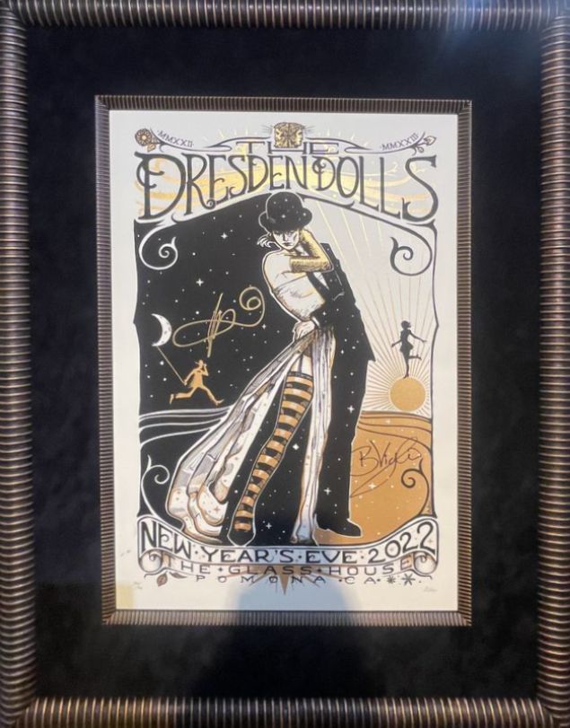 Framed Dresden Dolls New Year's Eve poster featuring an embracing couple, in black and gold tones, set against a starry sky.