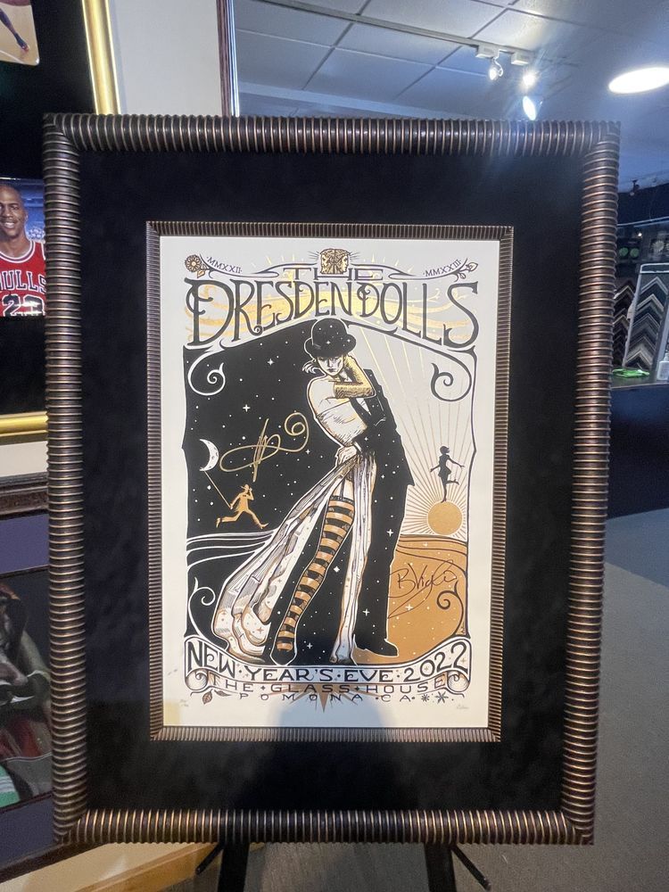 Framed Dresden Dolls New Year's Eve poster featuring an embracing couple, in black and gold tones, set against a starry sky.