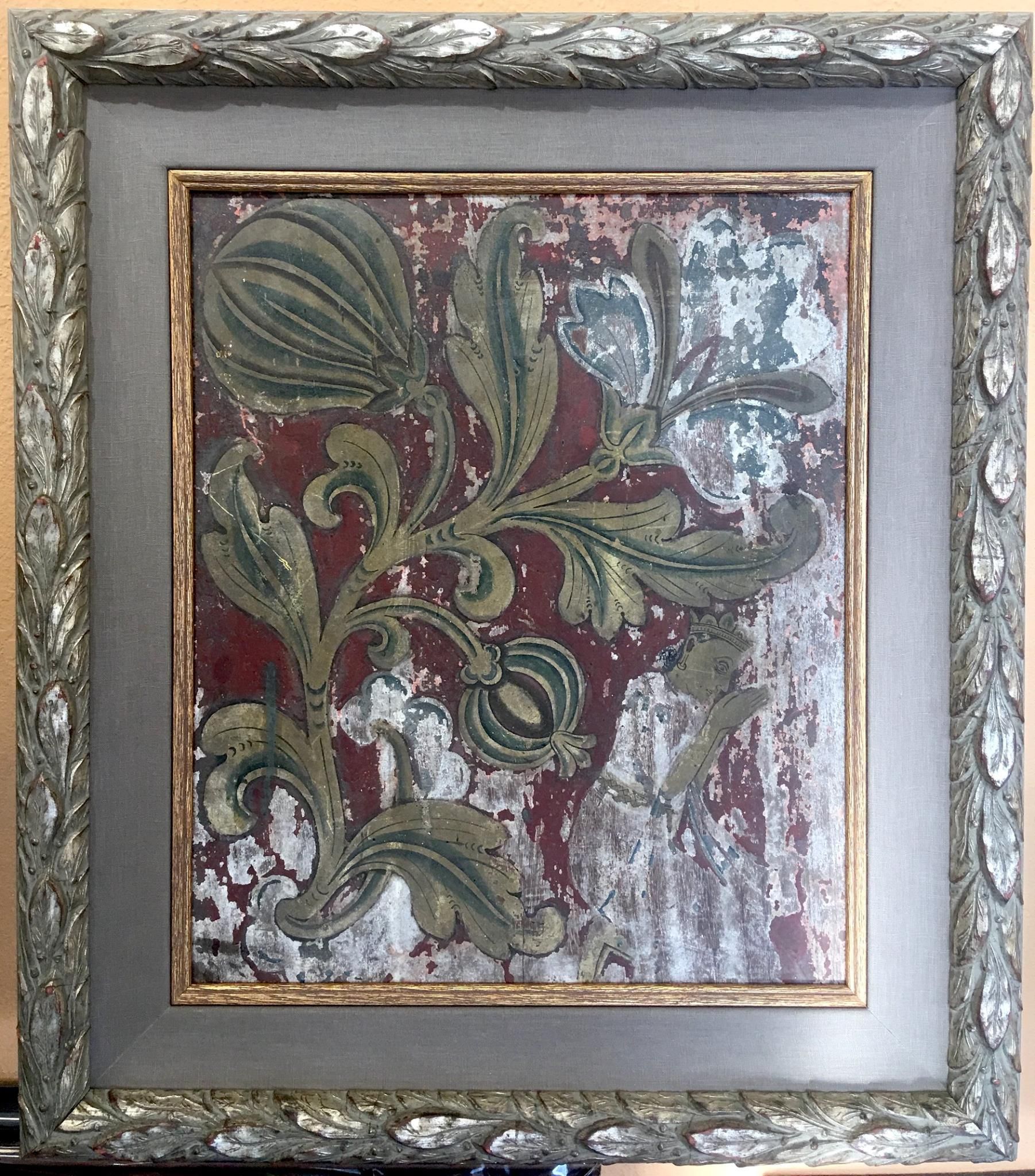 Framed artwork with distressed floral pattern in green and gold on a red background. The frame is ornate silver.