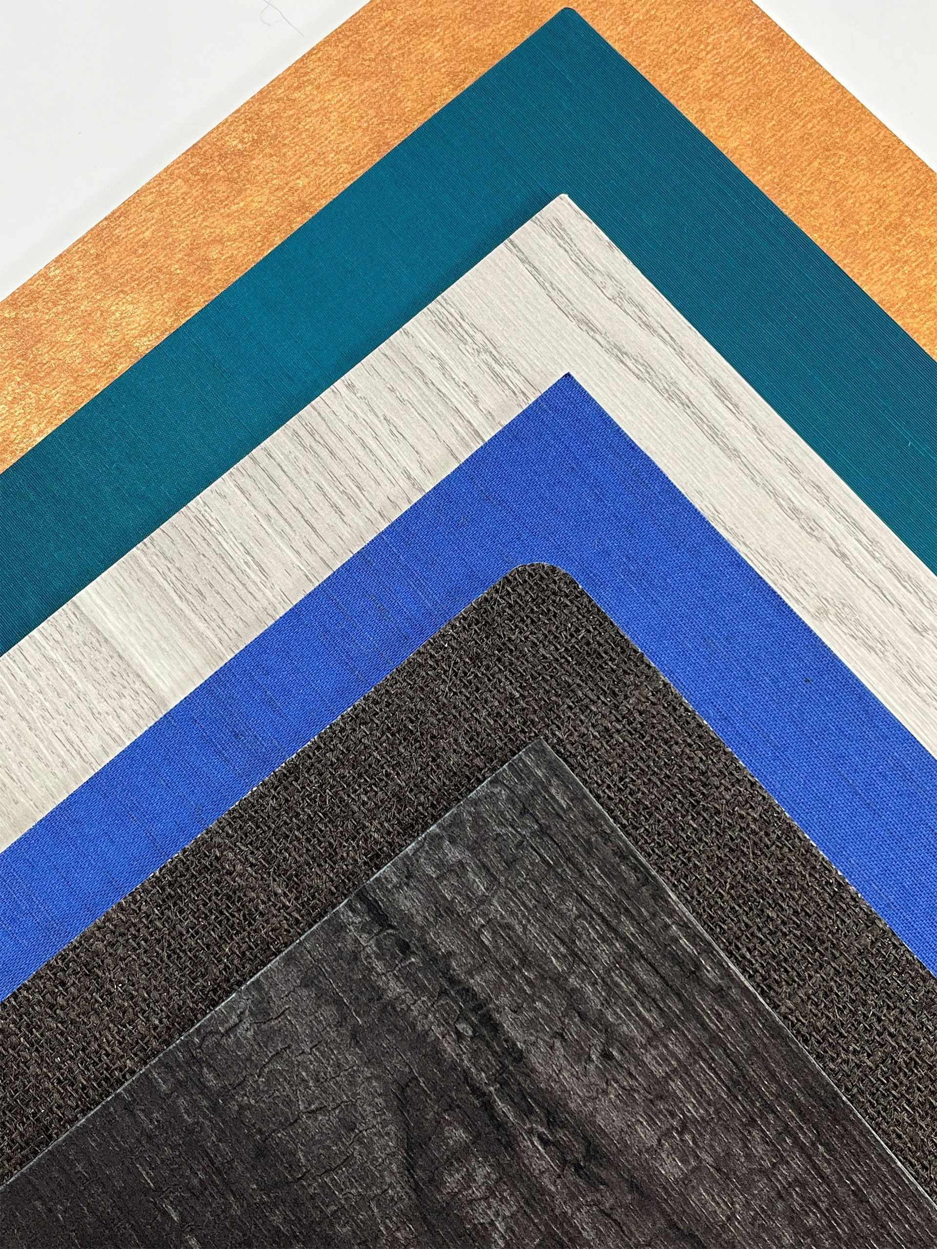 Five layered square fabrics in shades of orange, teal, white, blue, and gray, overlapping like a chevron.