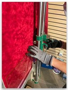 A person is using a machine to cut a piece of red fabric.