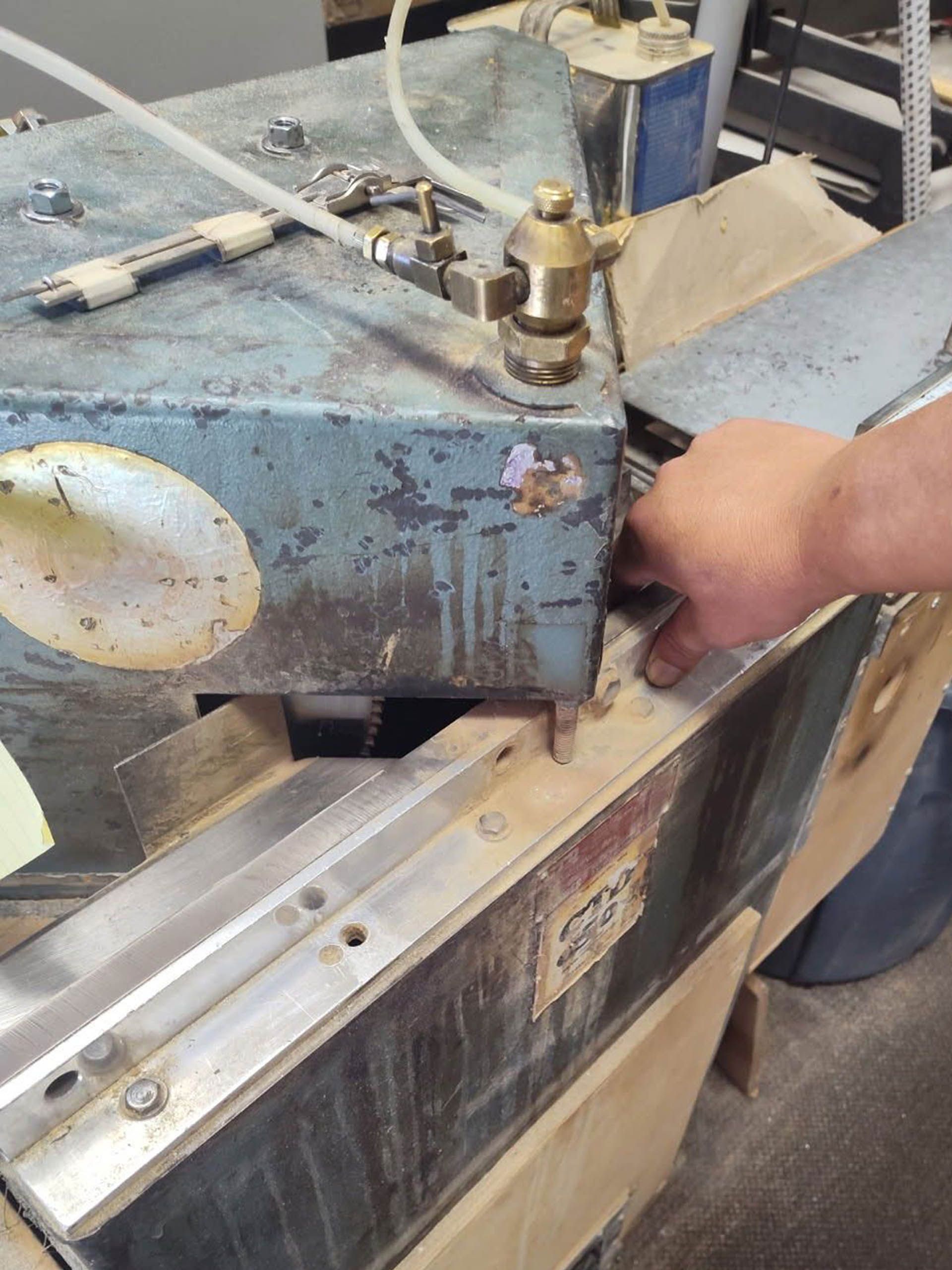 A man cutting the molding of a picture frame using a machine