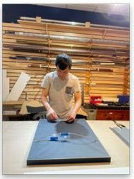 A man is cleaning a picture frame in a workshop.