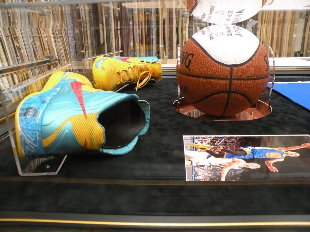 A pair of shoes and a basketball in a glass case