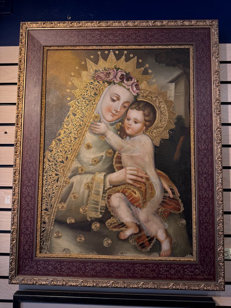 Painting of Mary holding baby Jesus, both with halos and detailed golden garments. They're set against a dark background, framed in ornate purple.