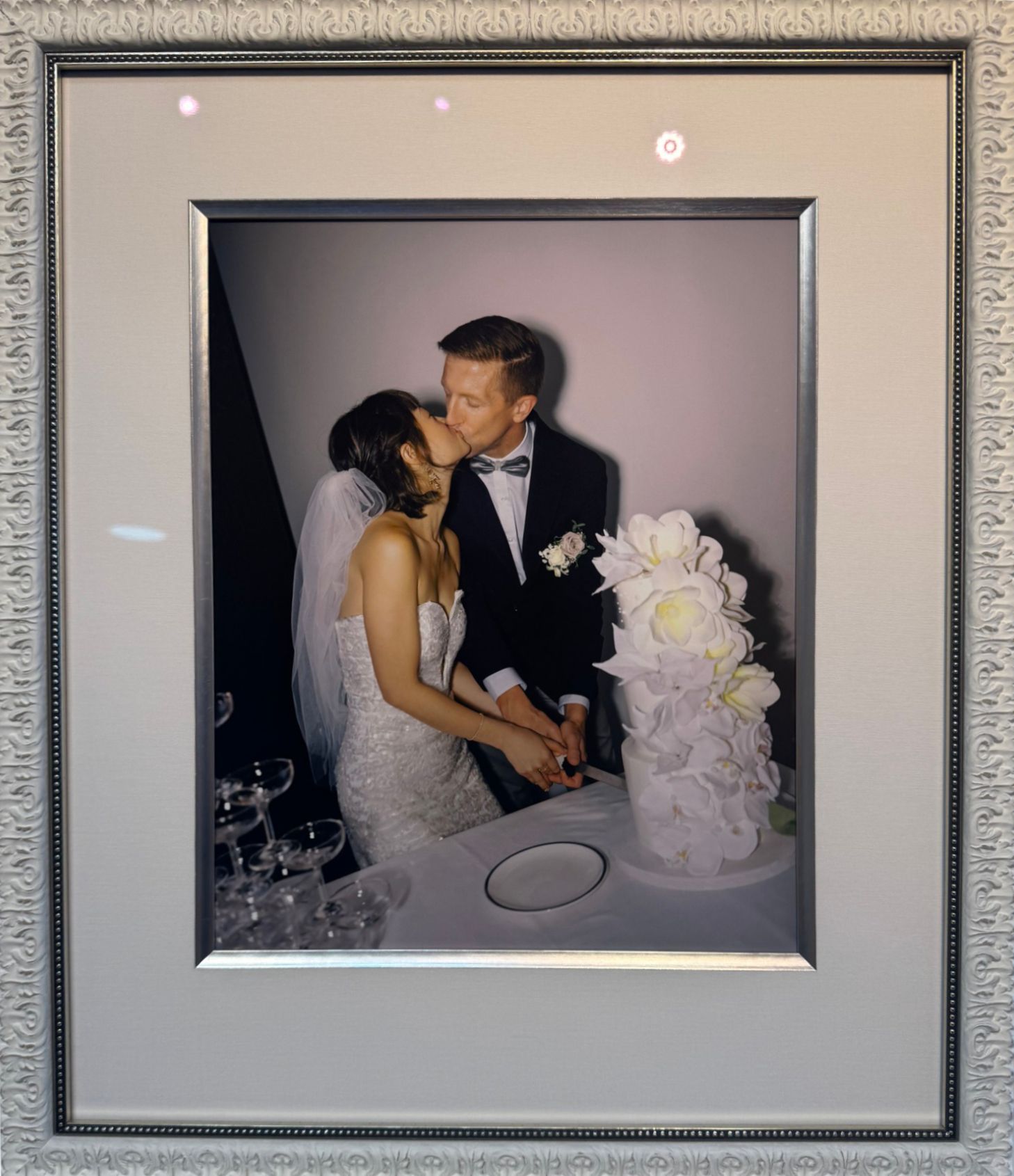 Framed wedding photo of a couple kissing beside a white floral cake display
