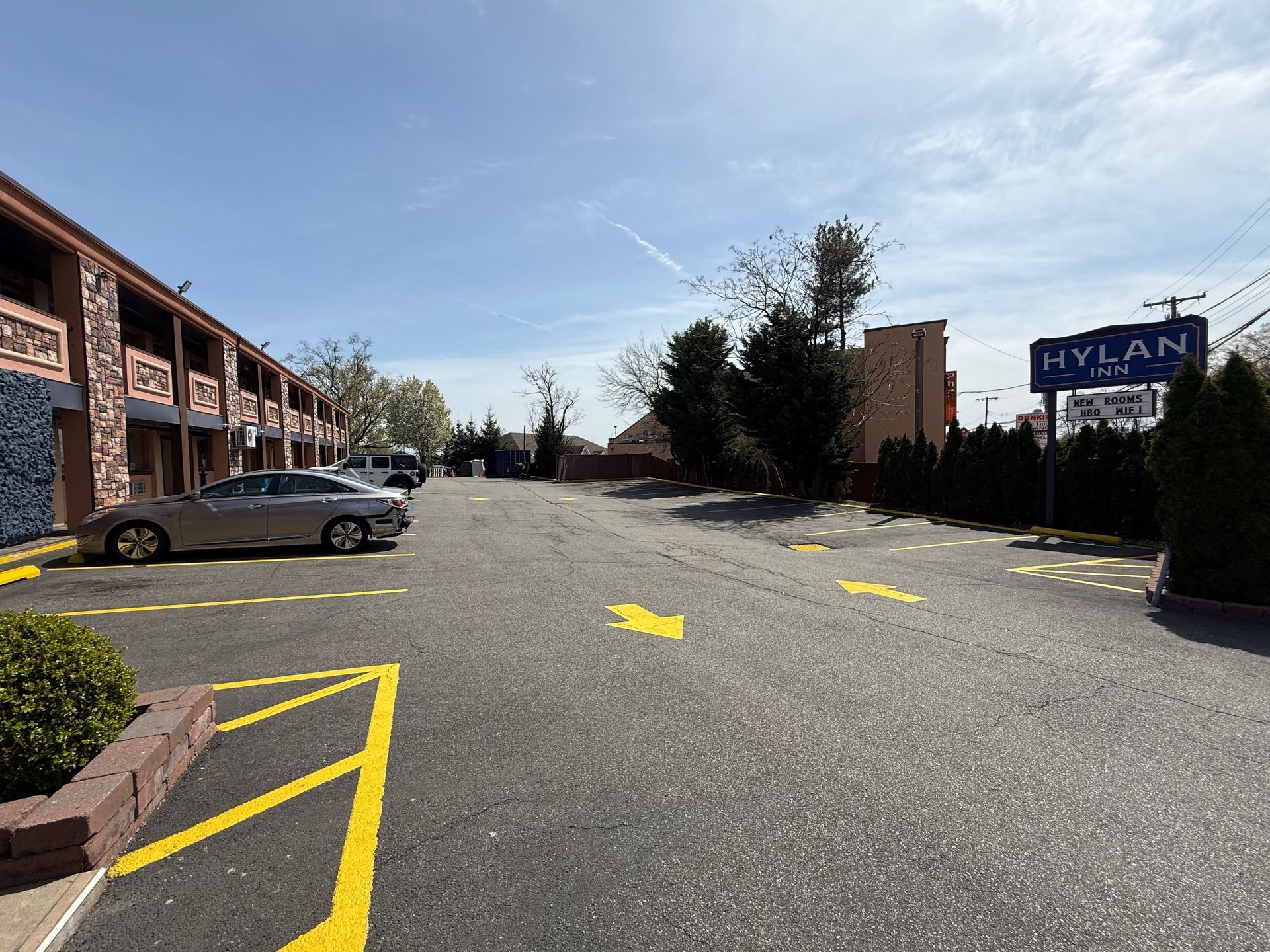 Parking lot with a car and directional arrows near the Mylan Motel sign on a sunny day.